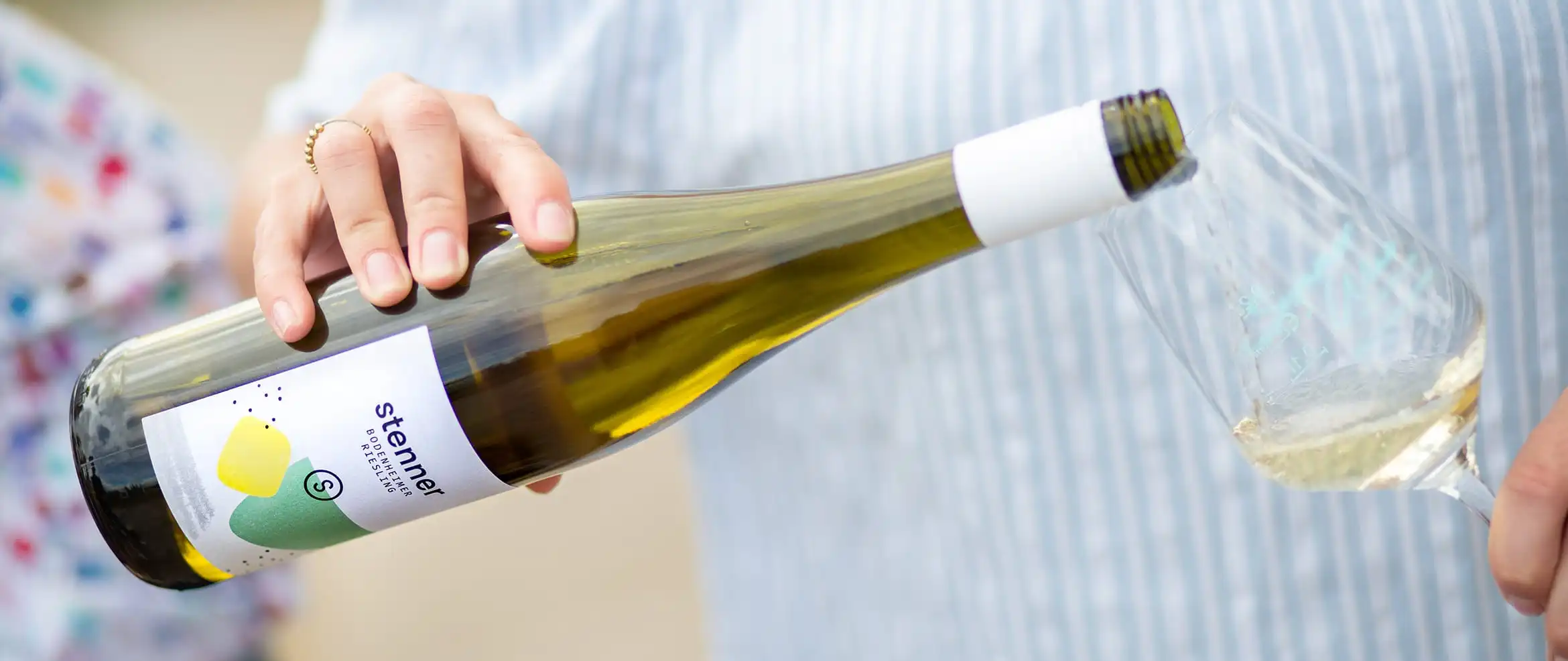 Auf dem Foto schenkt jemand aus einer Flasche von Weingut Stenner Wein in ein Glas ein
